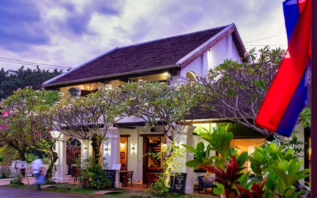 Residence Bassac boutique hotel facade at dusk with Lao flag, Champasak, Laos