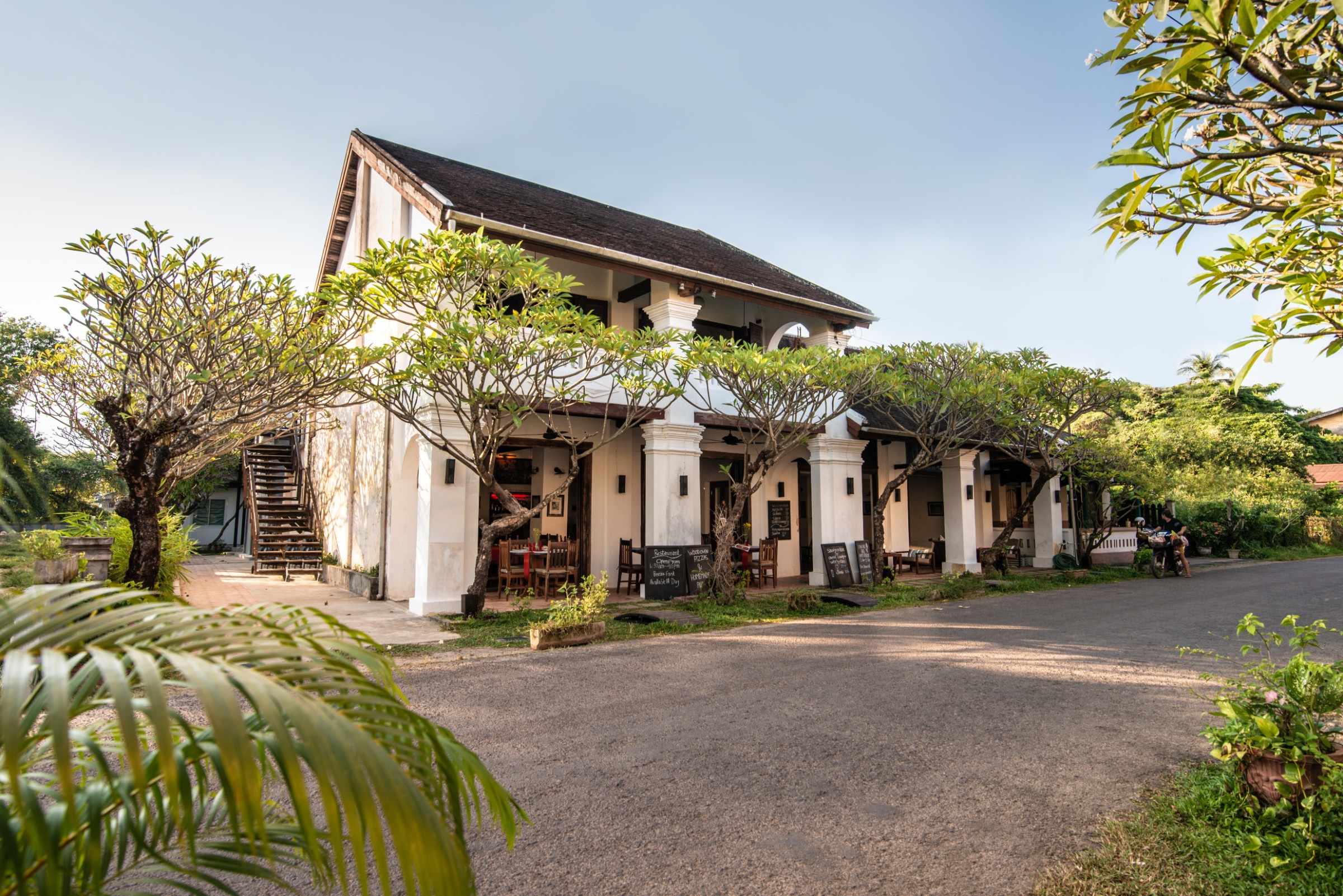 Facade of Residence Bassac boutique hotel under frangipani trees, Champasak, Laos